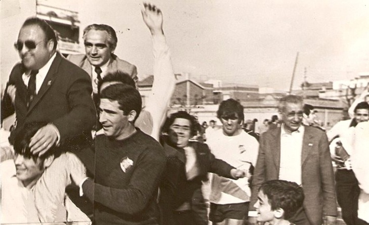 El vicepresident Andreu Galindo i l’entrenador Josep Monfort són enlairats pels aficionats de l’Horta després del 5 a 0 davant del Turó de la Peira al Feliu i Codina que segella el Títol de Lliga 75-76. El porter Riol, el lateral Puertas i el president Domingo Benavent són rodejats per eufòrics socis